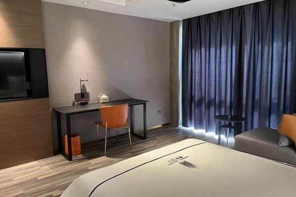 Ein modernes Hotelzimmer mit Bett, Schreibtisch, Stuhl und Fernseher.
