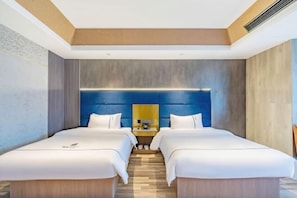 A modern hotel room with two beds, a wooden floor, a blue accent wall, and a small bedside table with a lamp. - Memory Graceful Hotel（Changzhou Yancheng Wuyue Plaza） (Changzhou)