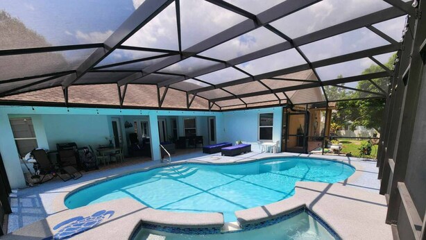 Una piscina exterior techada con sillas de descanso y un jacuzzi.