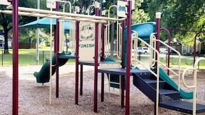 Un parque infantil con tobogán, estructuras para escalar y columpios.