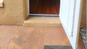 Una puerta que da a una habitación con piso de madera y una persiana blanca.