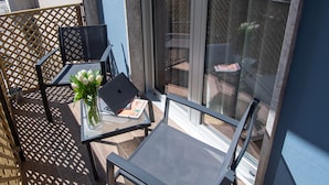 A balcony with a table, chairs, a laptop, and a vase of flowers.