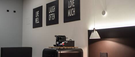 A modern room with a bed, a desk, and a coffee machine. There are three motivational posters on the wall.