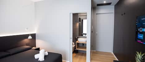 A modern hotel room with a bed, bedside table, and a TV mounted on the wall.