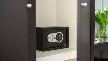 A black safe with a keypad on a white shelf.
