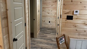 A wooden interior with a hallway leading to a room, a thermostat, and a vent. - Cozy cabin in the woods.   Close to boat ramp.  Shared 5 bay boat storage  (Counce)