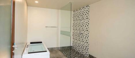 Une salle de bain moderne avec une douche à l’italienne, une baignoire et des toilettes.