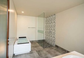 Une salle de bain moderne avec une douche à l’italienne, une baignoire et des toilettes.