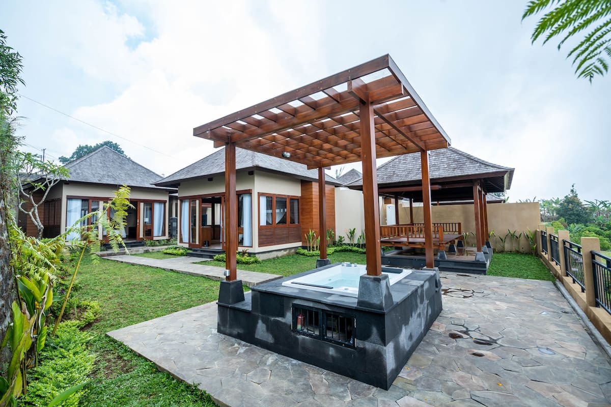 Een modern huis met een overdekt terras, een jacuzzi en een pad van stenen.