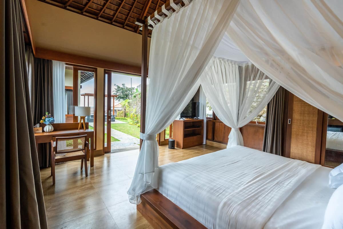 Een slaapkamer met een groot bed, houten meubels en uitzicht op de omgeving.