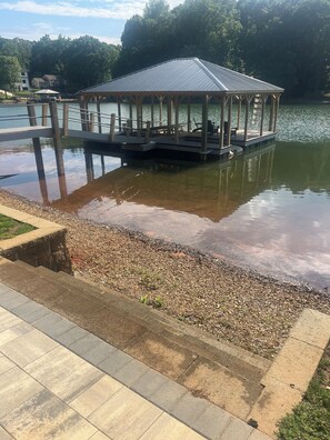 Ein Pavillon über dem Wasser, umgeben von einem Kiesstrand und einem Betonweg.
