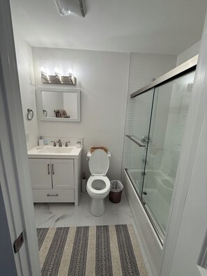 Un baño moderno con inodoro, lavamanos y ducha.
