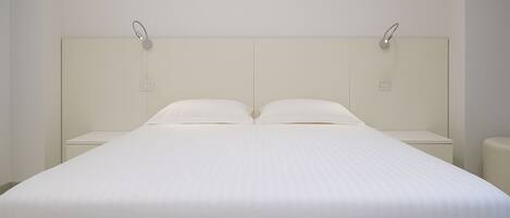 A large bed with a white headboard and two bedside tables.