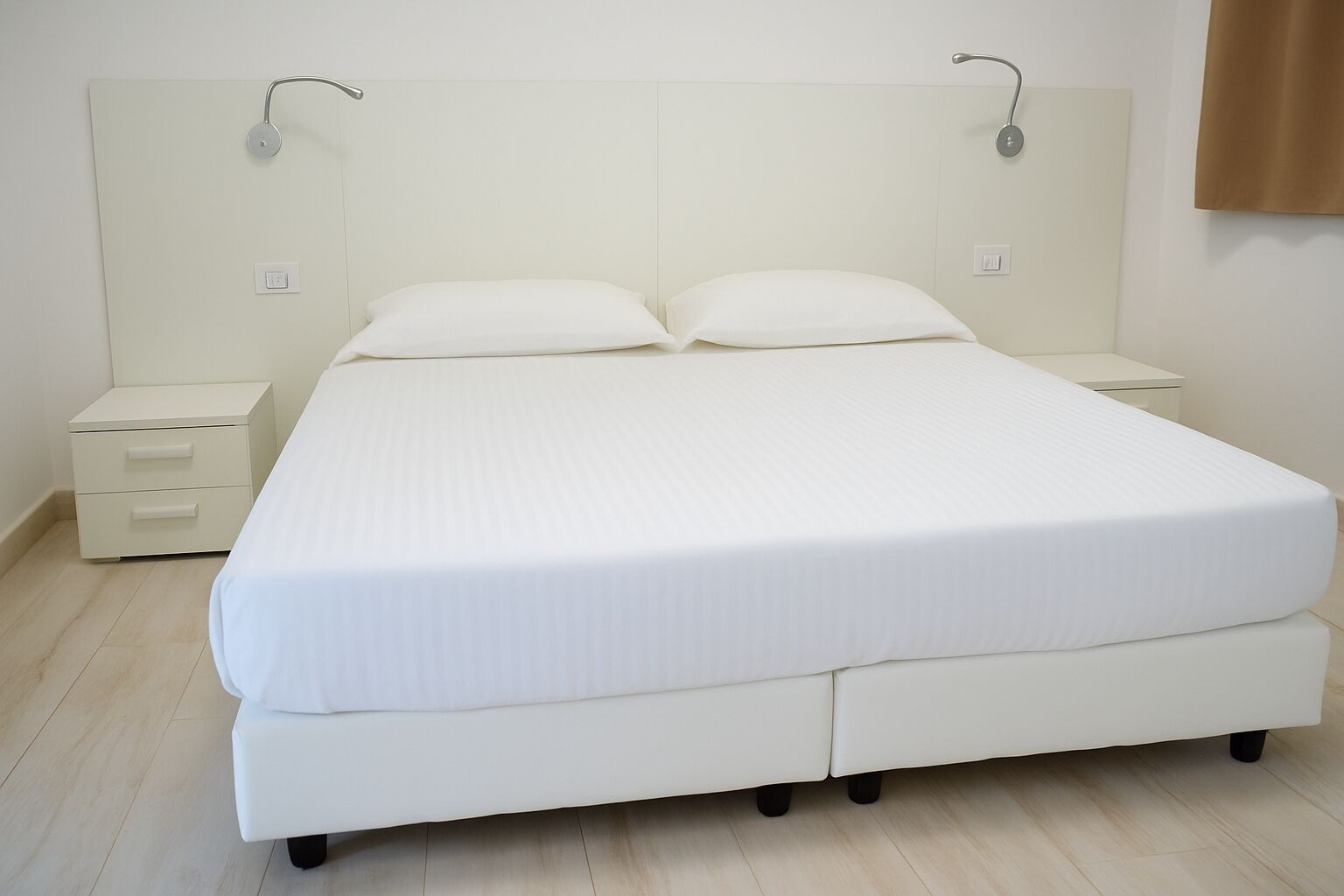 A bedroom with a large bed, two bedside tables, and a headboard with a light fixture.