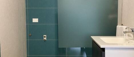 A modern bathroom with a toilet, sink, and shower.