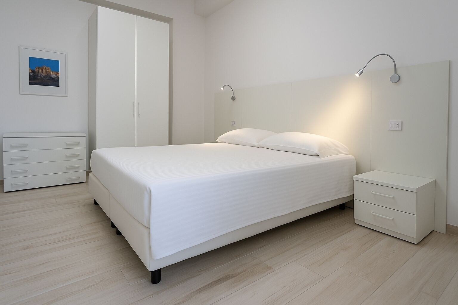 A modern bedroom with a bed, bedside tables, and a wardrobe.