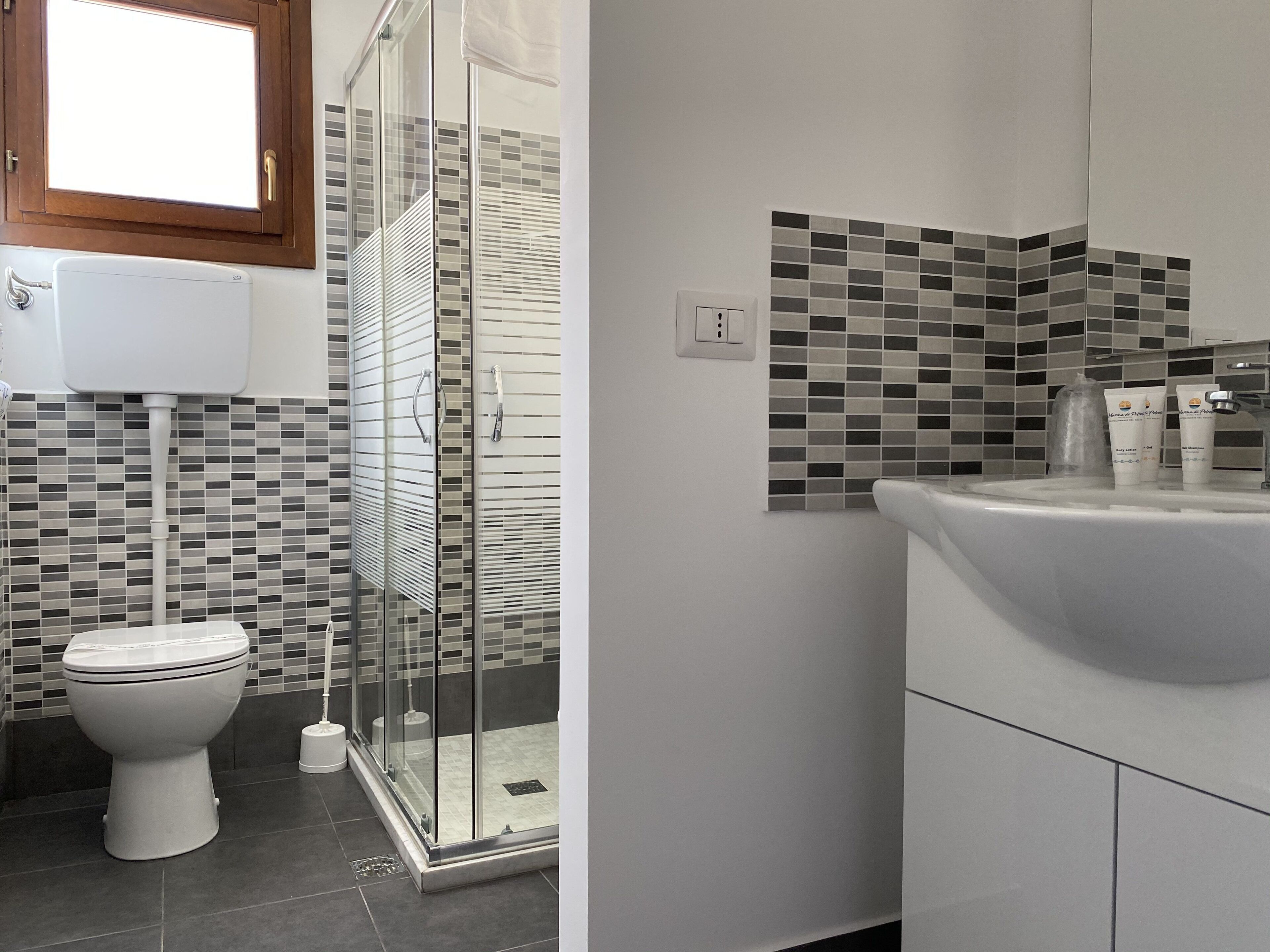 A modern bathroom with a toilet, shower, and sink.
