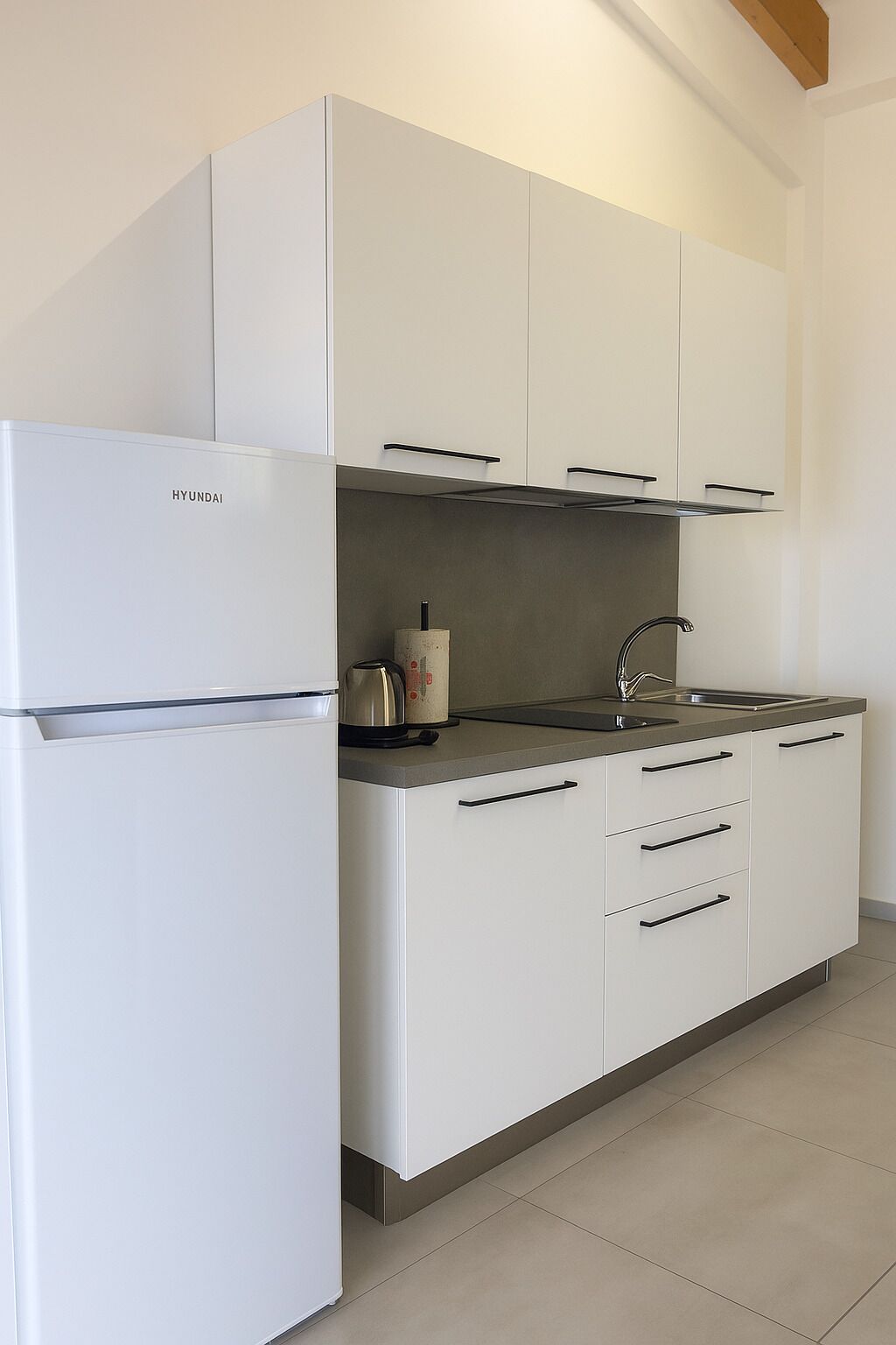 Una cocina moderna con armarios blancos, un lavamanos de acero inoxidable y un horno empotrado.