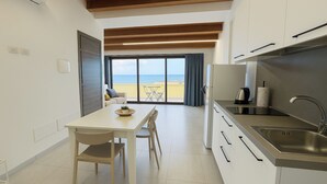 A modern kitchen with a dining area, large windows, and a view of the beach. - Marina di Petrolo Apartments (Castellammare del Golfo)