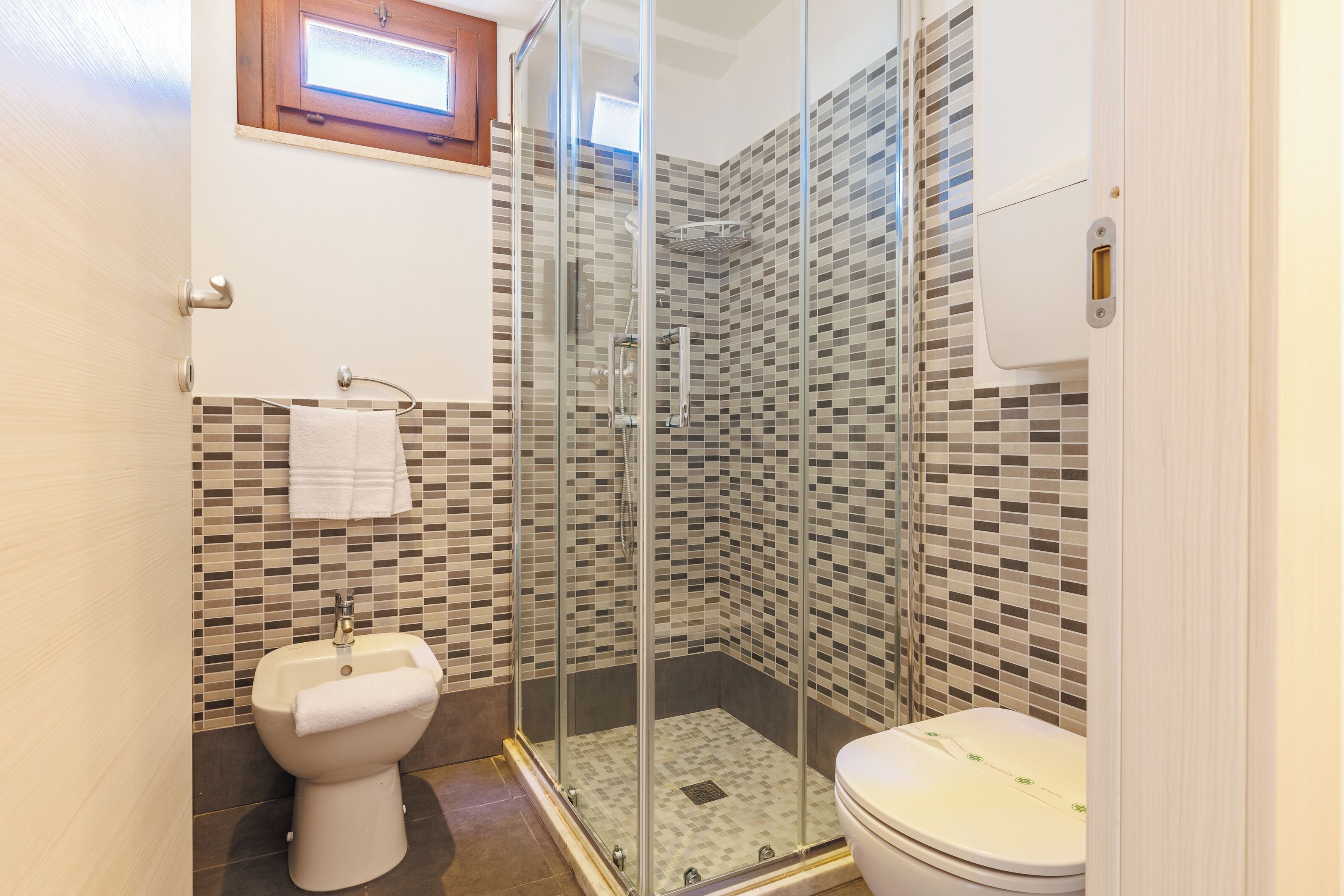 Un baño moderno con ducha envuelta en vidrio, inodoro y lavamanos.