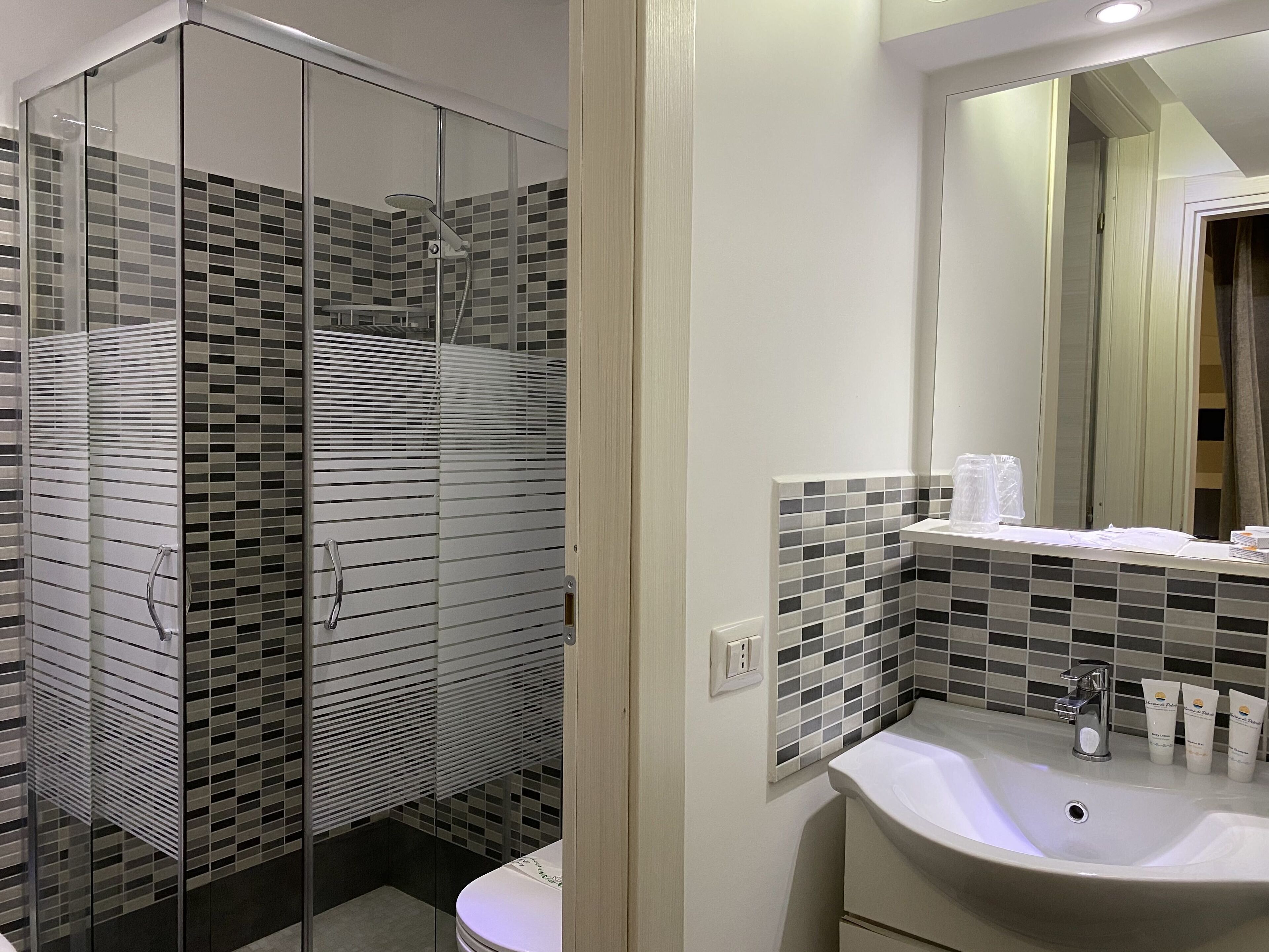A modern bathroom with a glass-enclosed shower, a white sink, and a tiled backsplash.