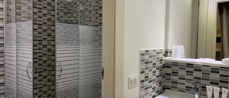 A modern bathroom with a glass-enclosed shower, a white sink, and a tiled backsplash.