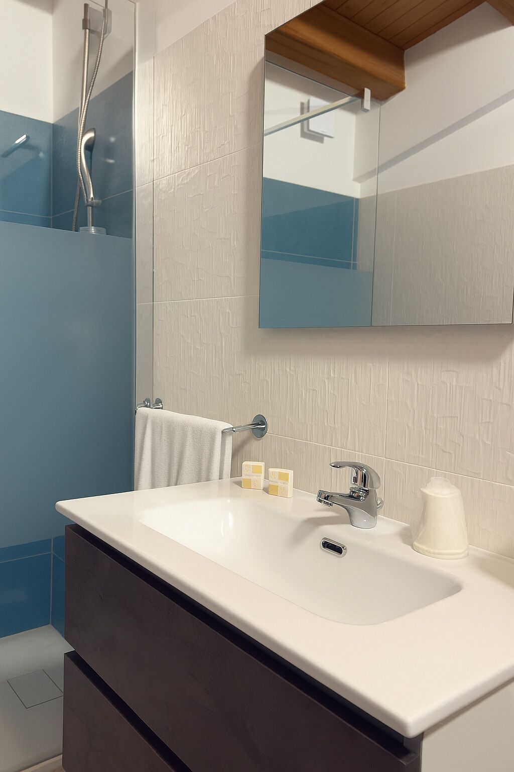 Un baño moderno con un lavamanos blanco, una cabina de ducha de vidrio y un espejo sobre el lavamanos.