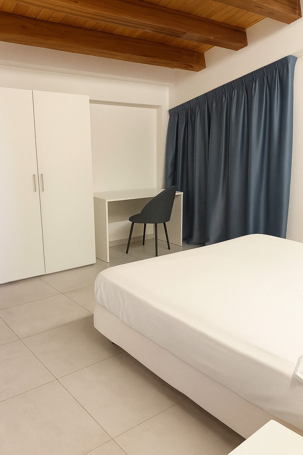A bedroom with a bed, a desk, and a chair.