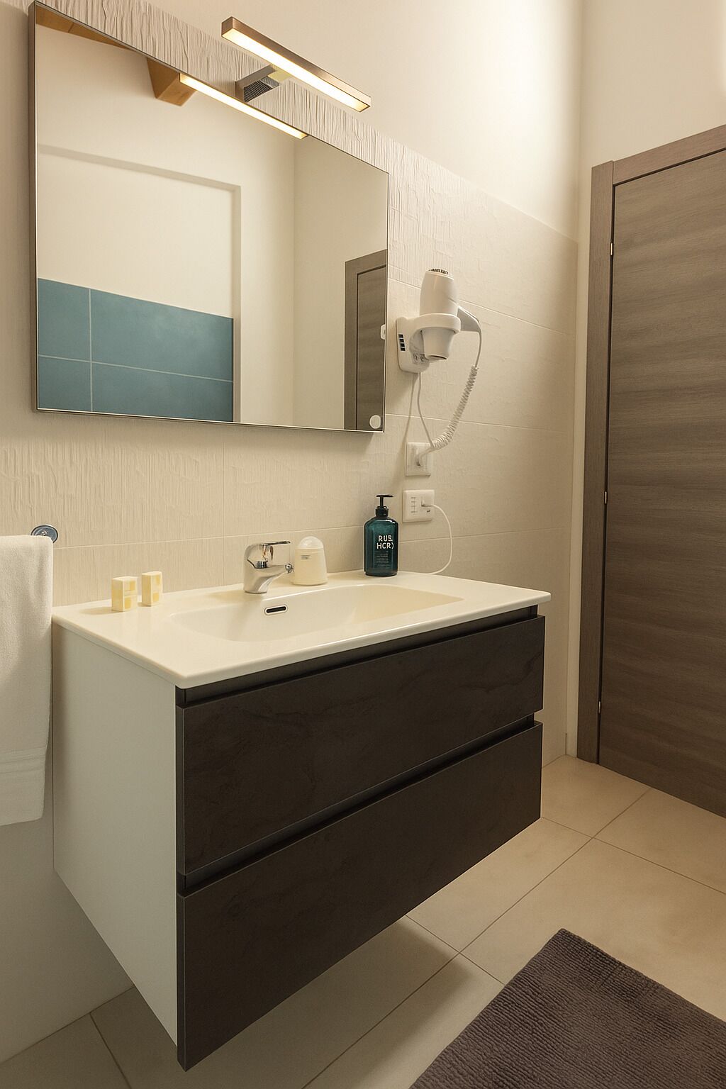 Un baño moderno con un lavamanos blanco, un mueble oscuro y un espejo arriba.