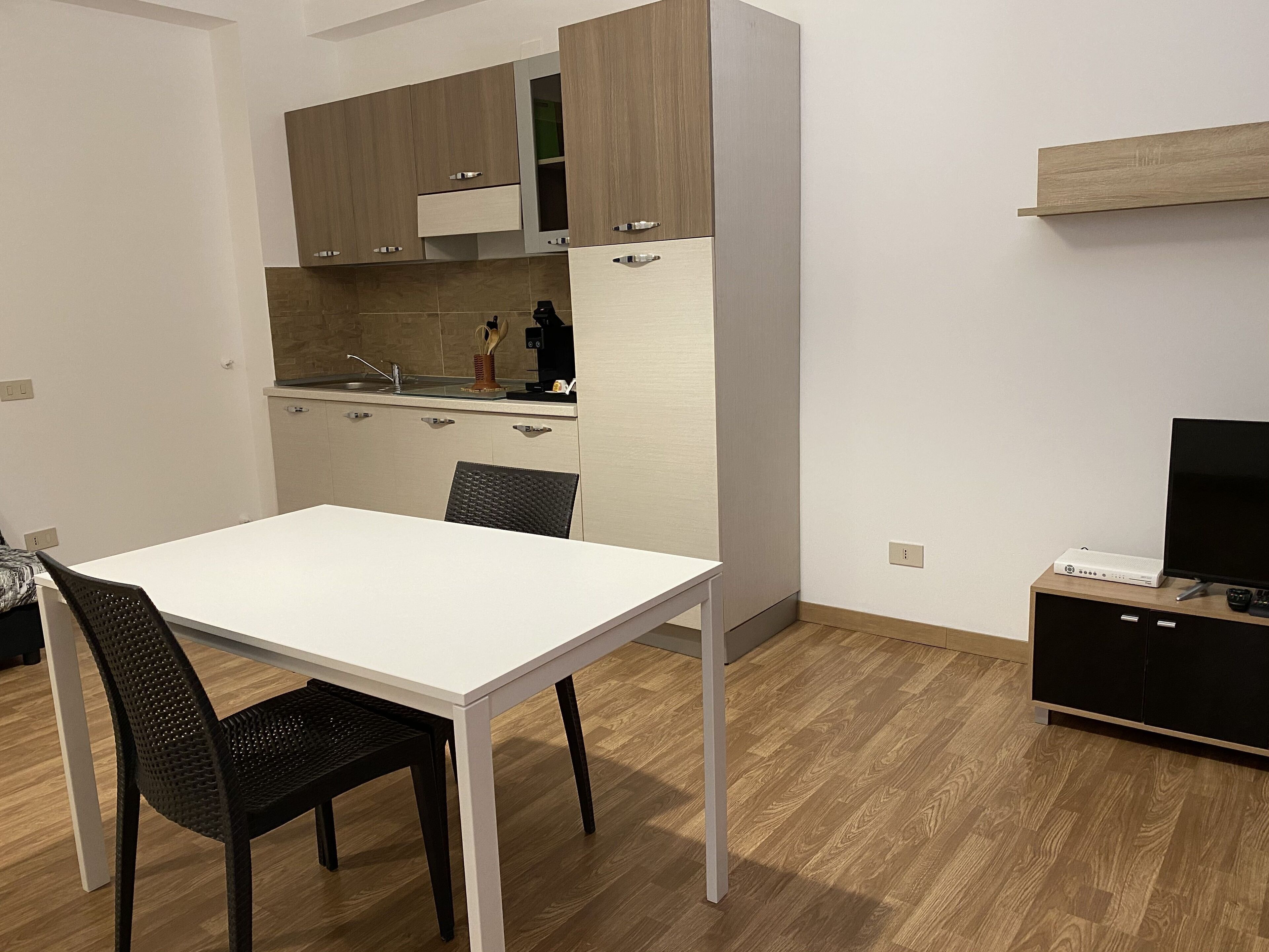 A compact kitchen with a white table and two chairs, a small countertop, and a built-in oven.