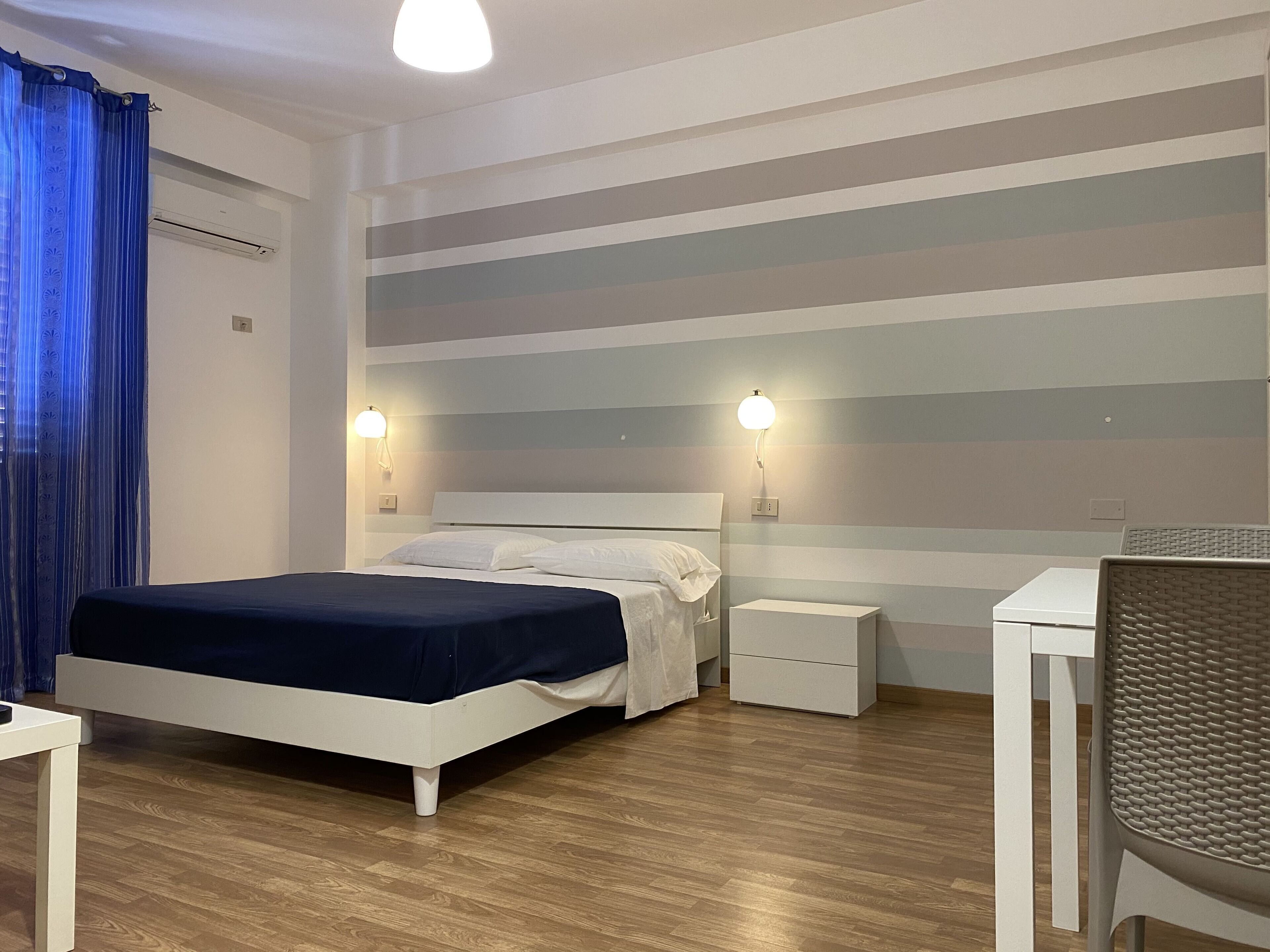 Un dormitorio con cama, mesitas de noche, un escritorio y una silla.