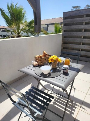 Pátio com mesa posta para o café da manhã, incluindo pão, flores e uma bebida.