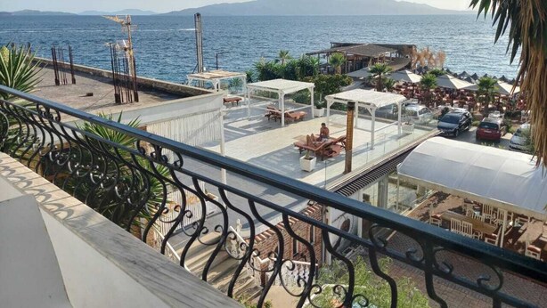 A seaside terrace with outdoor seating, a view of the sea, and distant mountains. - Sunset Aparthotel (Sarandë)