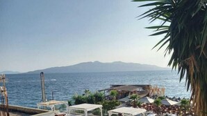 A seaside resort with outdoor seating areas, a pool, and a view of the sea and mountains. - Sunset Aparthotel (Sarandë)