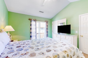 Un dormitorio con cama, televisión, cómoda y ventana con cortinas.