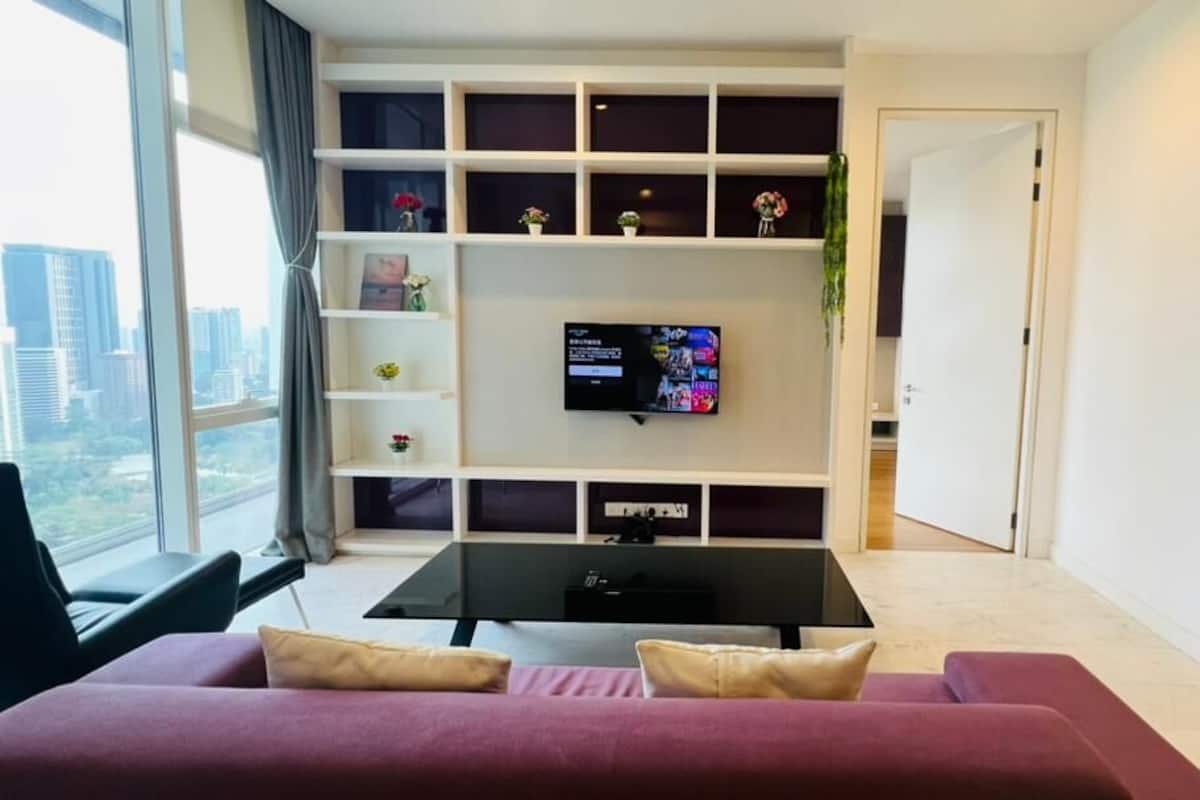 Ein modernes Wohnzimmer mit einem schwarzen Couchtisch, einem roten Sofa und einem Fernseher an einer weißen Wand.