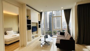 Ein modernes Hotelzimmer mit einem Bett, einer Couch, einem Glastisch und einem Fernseher an der Wand.