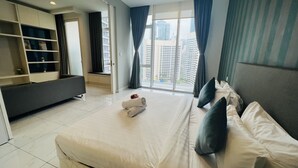 Ein modernes Hotelzimmer mit einem großen Bett, einer Sitzecke, einem integrierten Fernseher und Blick auf die Stadt durch große Fenster.