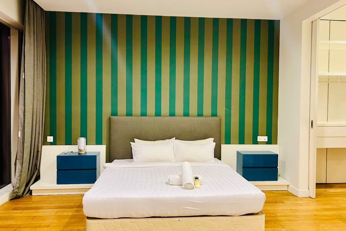 Ein ordentlich bezogenes Bett mit weißen Leinentüchern, zwei Nachttische mit blauen Schubladen und eine grün-gestreifte Wand dahinter.