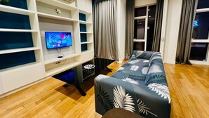Ein modernes Wohnzimmer mit Sofa, Fernseher und eingebauten Regalen.