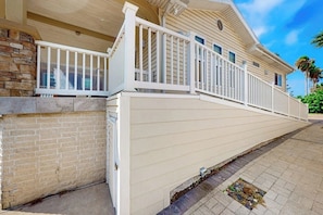 A two-story house with a white exterior, a stone foundation, and a covered porch with white railings.