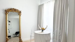 A room with a large ornate mirror, a round table with a crown-shaped centerpiece, and clear chairs. - Jazz Hotel Palm Springs (Palm Springs)