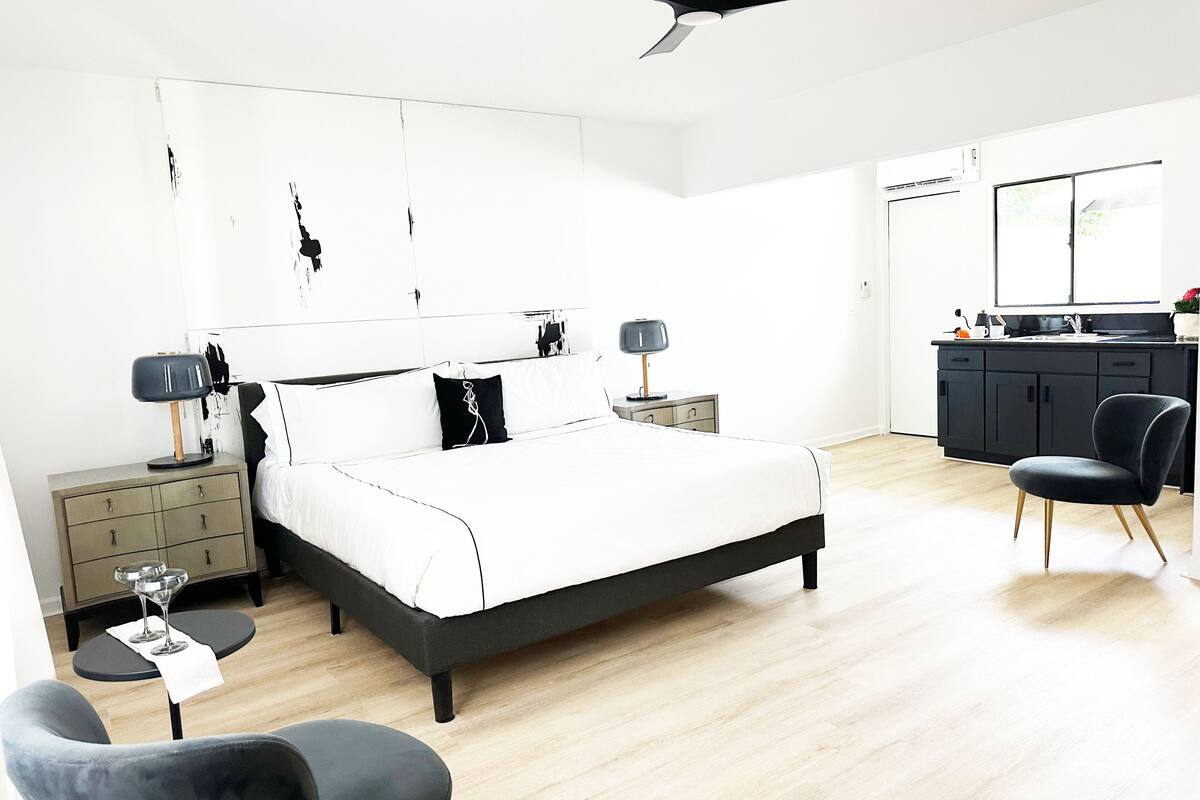 A modern bedroom with a bed, bedside tables, a desk, and a chair.
