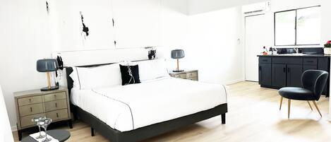 A modern bedroom with a bed, bedside tables, a desk, and a chair.