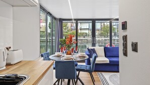 Een moderne keuken met een eethoek, een blauwe bank en grote ramen met uitzicht op de stad.