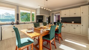 A modern kitchen with a wooden dining table, green chairs, and white cabinets.