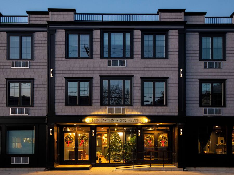 A hotel with a classic facade, large windows, and a Christmas tree outside.