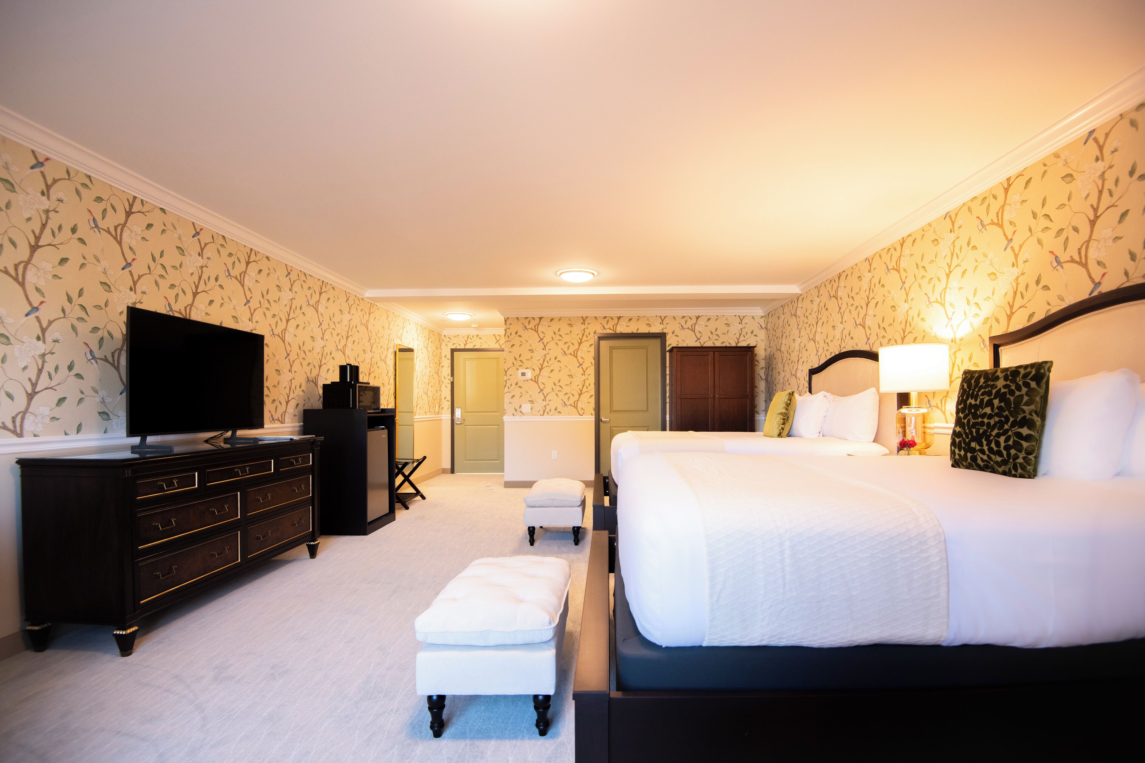 Une chambre d’hôtel avec un grand lit, une commode, une télévision et un bureau avec une chaise.