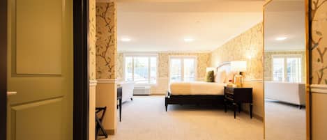Hotellihuone, jossa on sänky, yöpöytä, lamppu ja suuri peili.