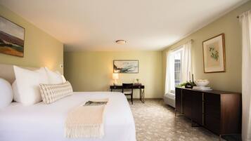 A hotel room with a large bed, a desk, and a dresser.